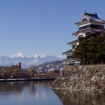 Donjon und Mizuhori der Burg von Matsumoto (Matsuyama-jō), im Hintergrund die Nordalpen